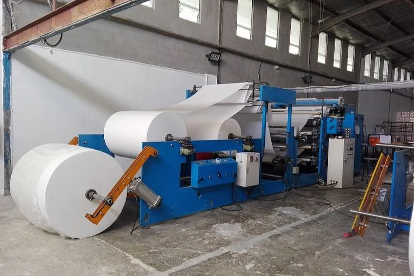 Industrial paper machine production line showing large rolls of paper. Alcon makes cutting blades for paper and packaging industry.